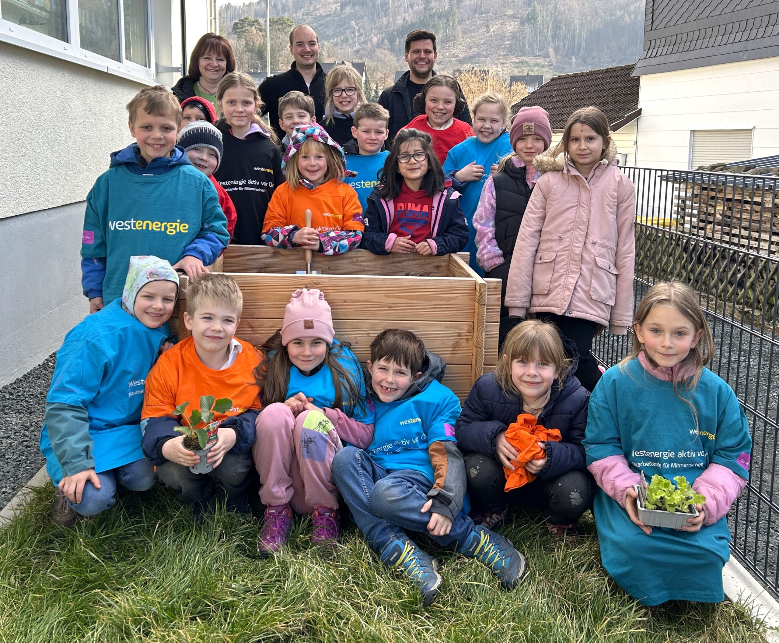 Von links nach rechts: Gaby Limper, Jann Burholt und kommunaler Partnermanager der Westenergie Jonas Leyener zusammen mit Kindern des Teilstandortes Niederlaasphe. (Foto: Westenergie / Victoria Baumann)